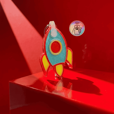 Brightly colored rocket-shaped NFC pet ID tag with a keyring, designed for dogs and cats — Shiloh's House smart NFC pet tag with free companion Lohji app.