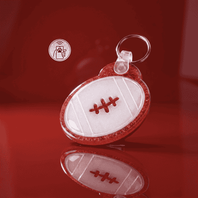 NFC pet ID tag shaped like a football with red stitching, designed for dogs and cats — Shiloh's House smart NFC pet tag with free companion Lohji app.