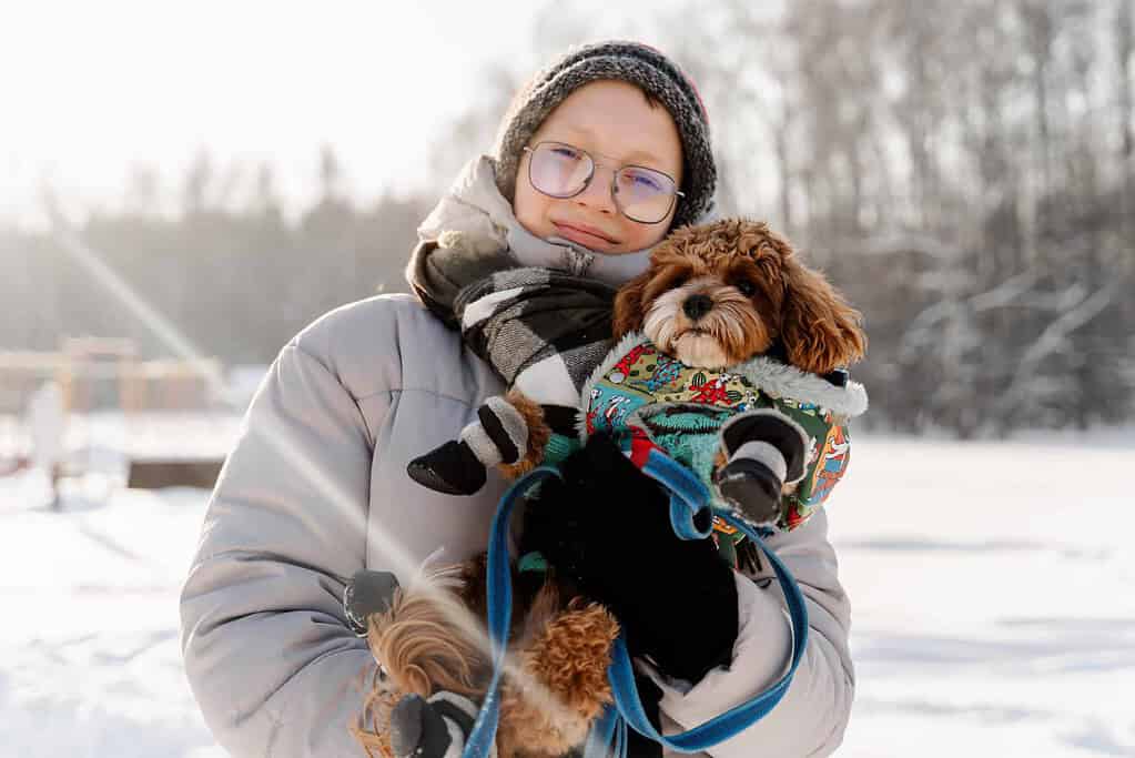 Woman holding dog in winter with pet ID tag in snow.
