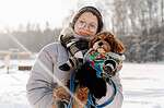 Woman holding dog in winter with pet ID tag in snow.